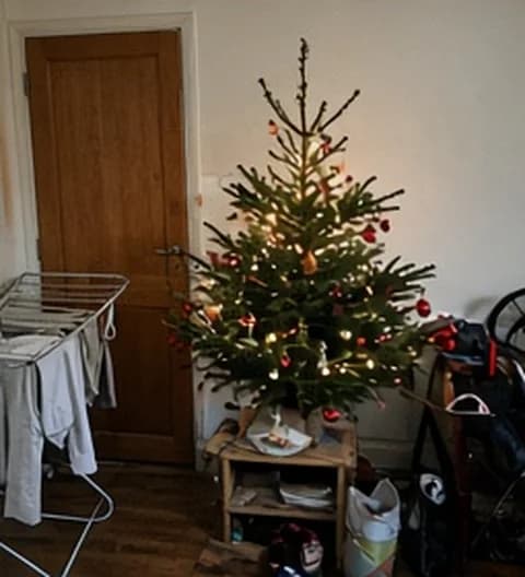 Un sapin imparfait installé dans un petit appartement en ville, photo partagée depuis Italie